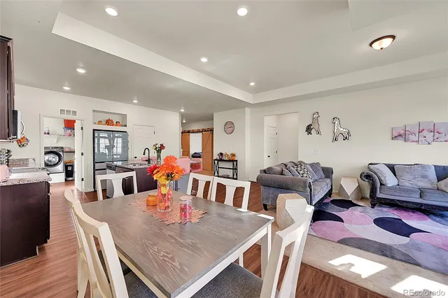 a kitchen with stainless steel appliances granite countertop a stove a refrigerator a sink a dining table and chairs with wooden floor