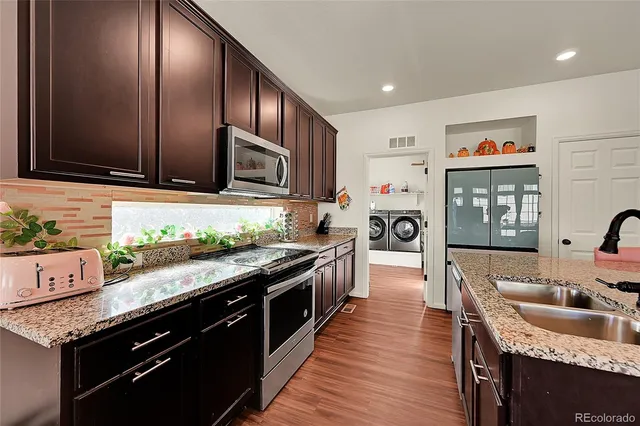 a kitchen with stainless steel appliances granite countertop lots of counter top space and wooden floor