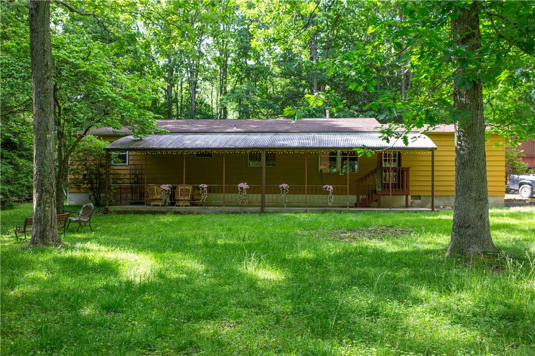 A welcoming front porch extends across this charming forest-surrounded residence, offering a tranquil retreat.