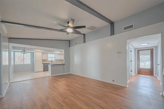 a view of empty room with wooden floor and fan