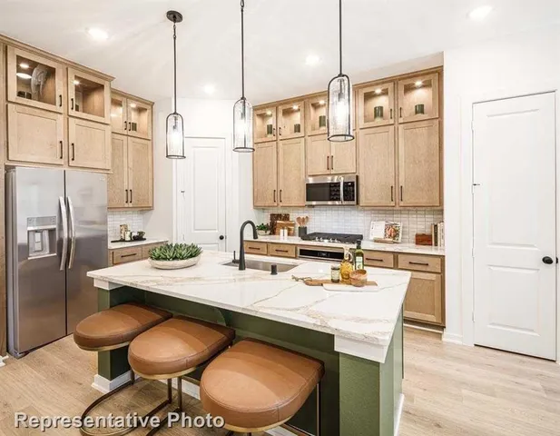 a kitchen with stainless steel appliances a refrigerator a sink a stove and white cabinets