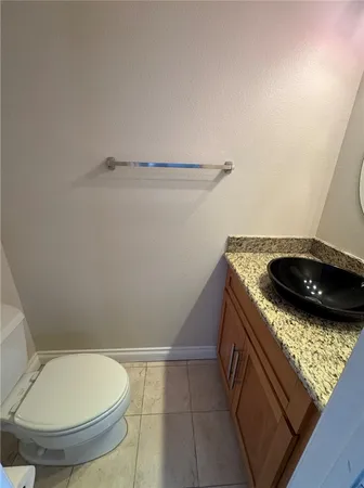 a bathroom with a granite countertop toilet and a sink