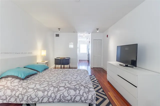 a bedroom with a bed a chair and potted plant on the table