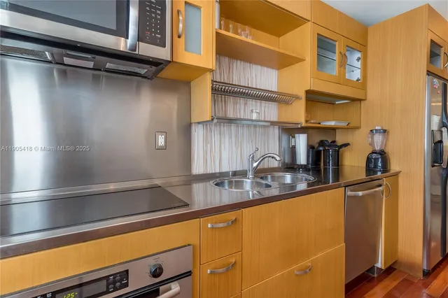 a kitchen with stainless steel appliances granite countertop a sink and a stove next to a window