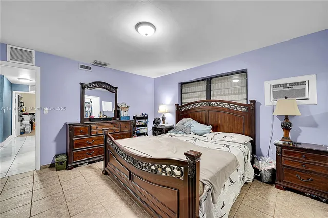 a bedroom with a bed and a flat tv screen on dresser