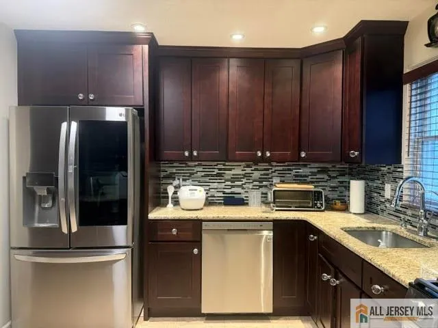 a kitchen with stainless steel appliances granite countertop a refrigerator a sink and wooden cabinets