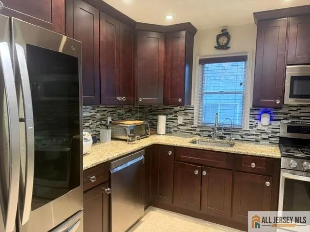 a kitchen with stainless steel appliances granite countertop wooden cabinets a refrigerator and a sink