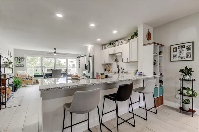 a dining hall with stainless steel appliances kitchen island granite countertop a dining table chairs and white cabinets