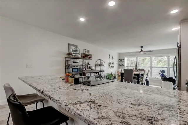 a kitchen with stainless steel appliances kitchen island granite countertop a stove a refrigerator a sink a dining table and chairs with wooden floor