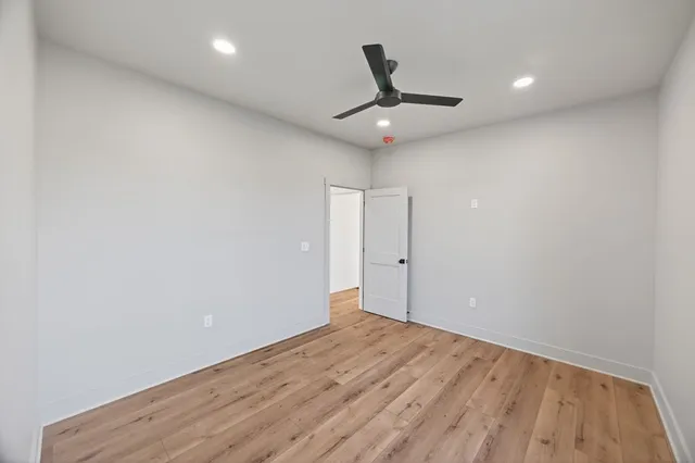 a view of empty room with wooden floor and fan