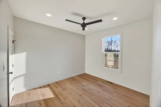 an empty room with wooden floor and ceiling fan