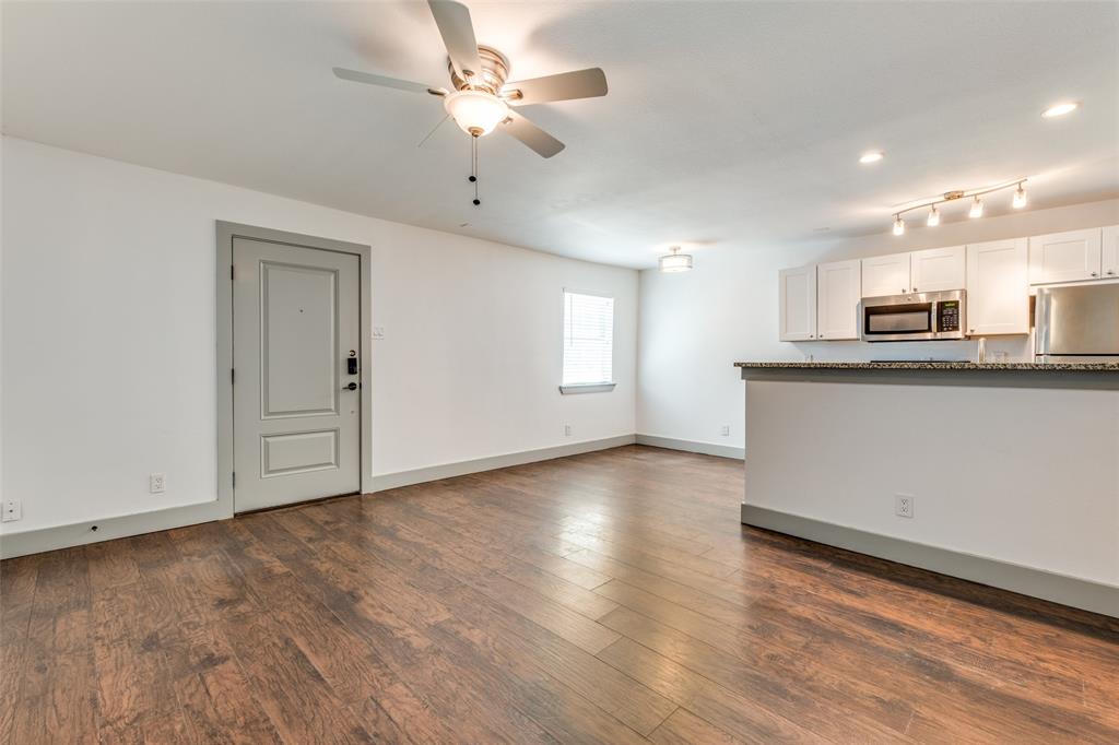 4633 Fairmount Street, Unit 109 Dallas, TX 75219 - Photo 3 of 14 Spacious living area featuring wood-finish flooring and a ceiling fan