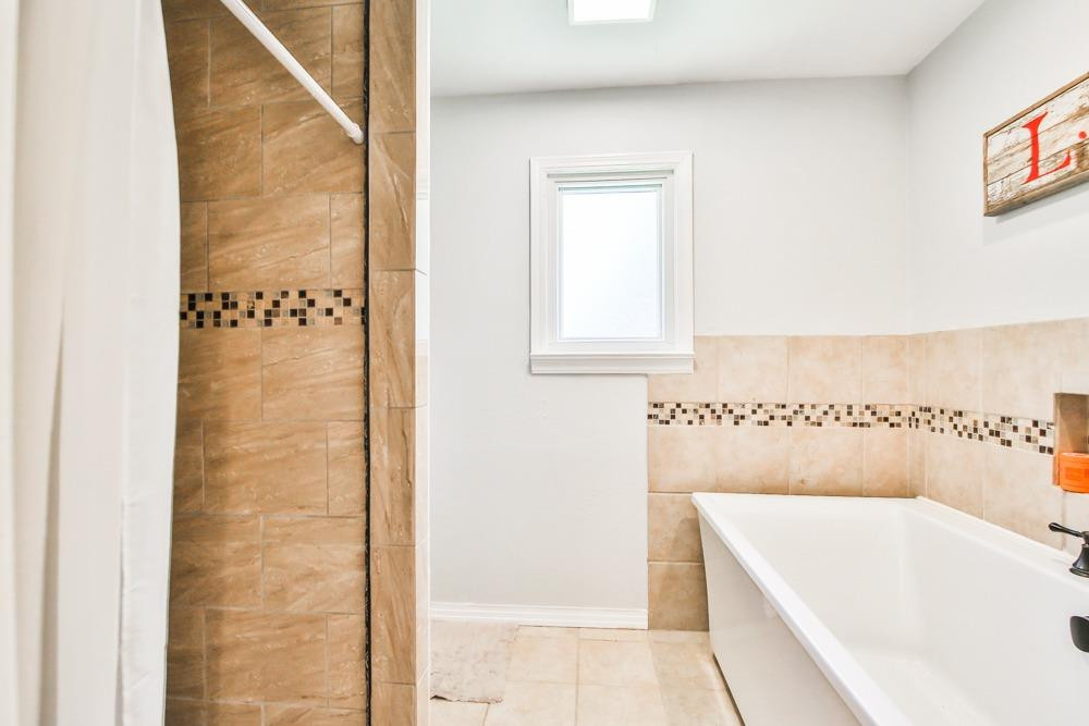 4915 79th Street Lubbock, TX 79424 - Photo 19 of 37 a bathroom with a bath tub and shower