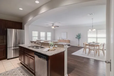 a kitchen with stainless steel appliances granite countertop a table chairs stove and refrigerator