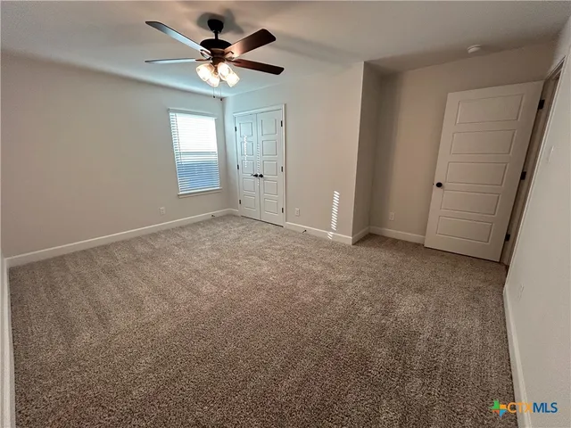 an empty room with windows and fan