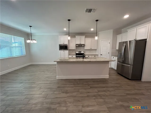 a view of kitchen with stainless steel appliances granite countertop a stove a refrigerator a sink and a microwave