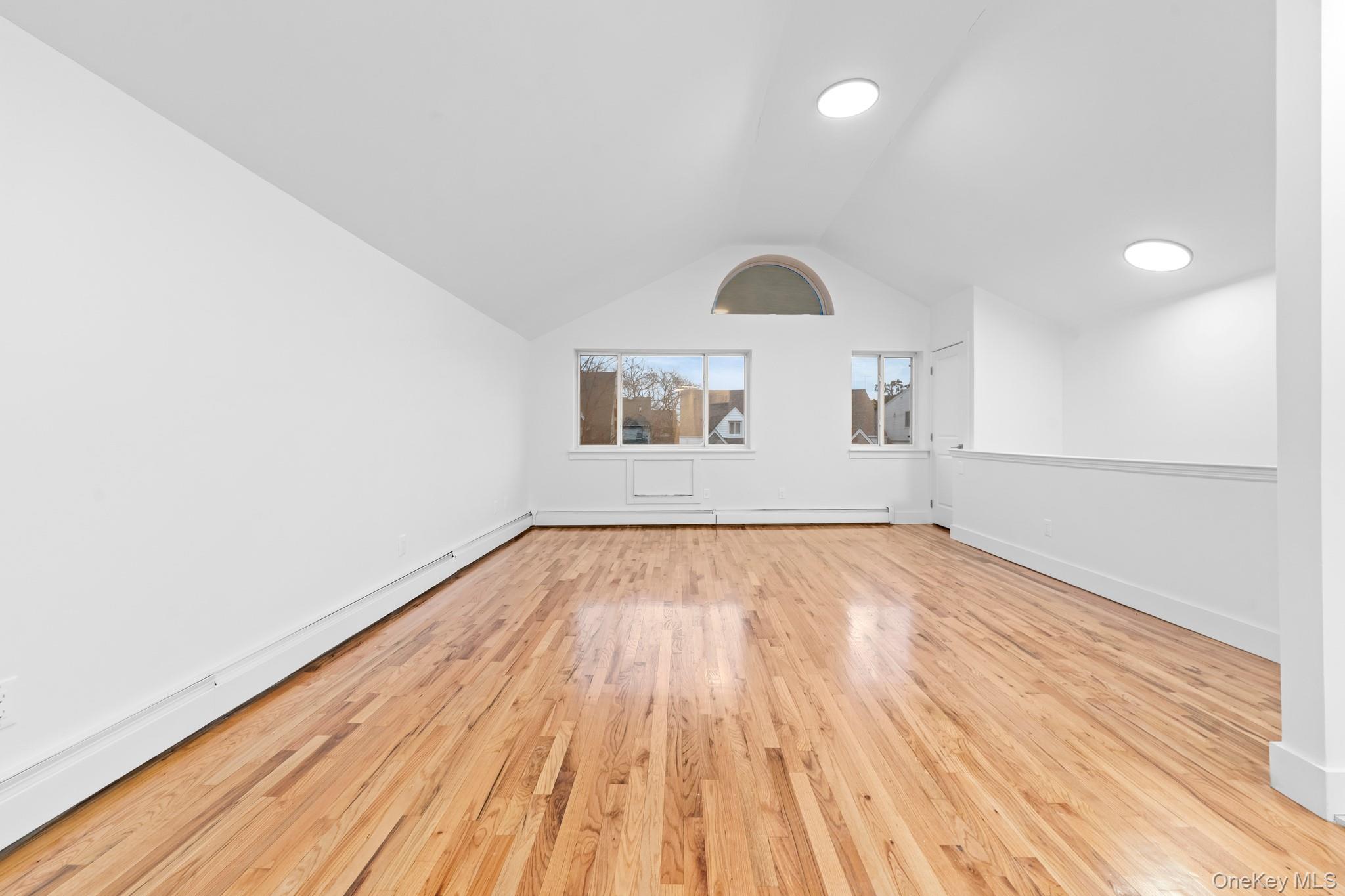 83-32 159th Street Queens, NY 11432 - Photo 8 of 15 an empty room with wooden floor and windows