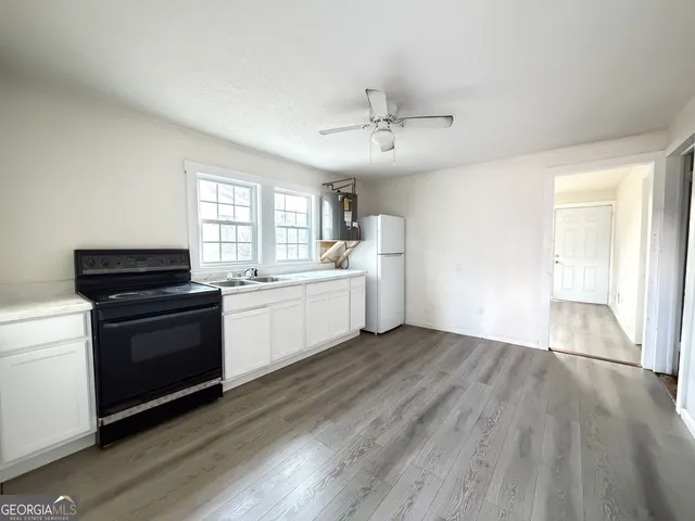 a kitchen with a sink wooden floor and white appliances