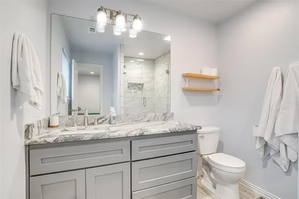 a bathroom with a granite countertop toilet sink and mirror