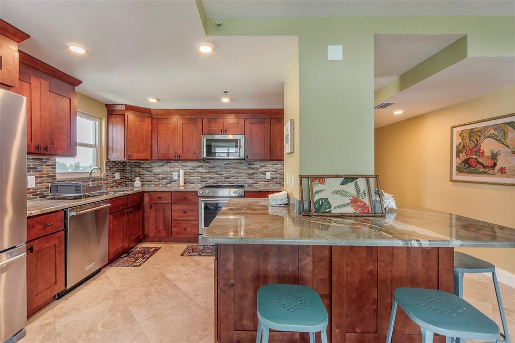15400 Gulf Boulevard, Unit 505 Madeira Beach, FL 33708 - Photo 13 of 27 a kitchen with a stove a sink a microwave a dining table and chairs
