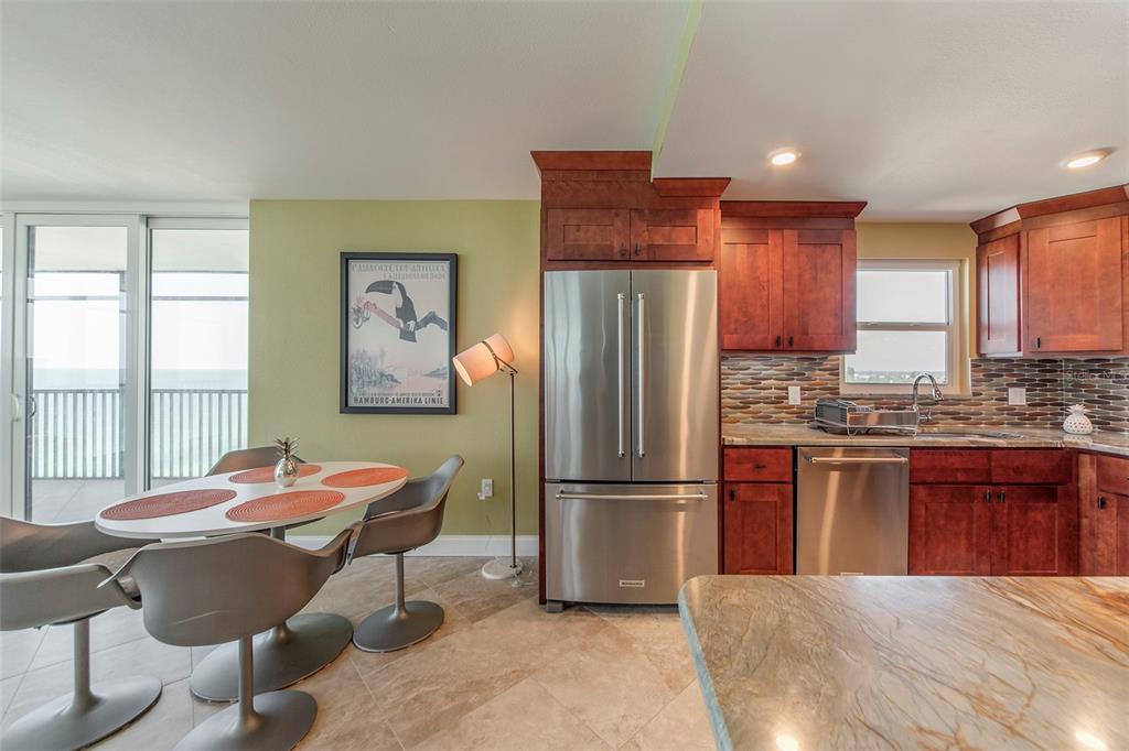 15400 Gulf Boulevard, Unit 505 Madeira Beach, FL 33708 - Photo 14 of 27 a kitchen with stainless steel appliances granite countertop a refrigerator a sink dishwasher a stove and a dining table with wooden cabinet