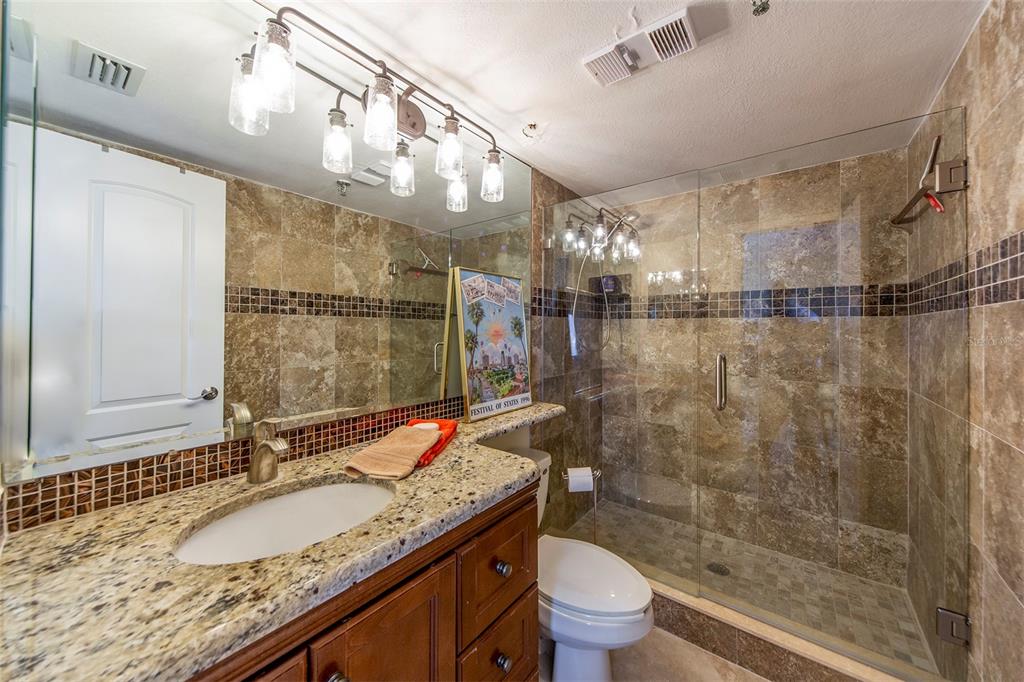15400 Gulf Boulevard, Unit 505 Madeira Beach, FL 33708 - Photo 19 of 27 a bathroom with a granite countertop sink a toilet and shower