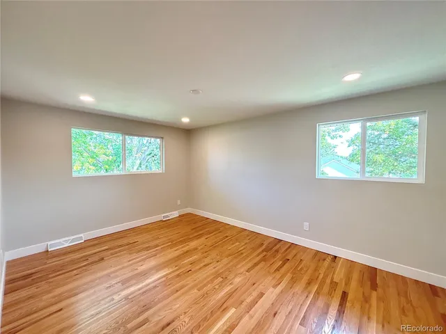 an empty room with wooden floor and windows