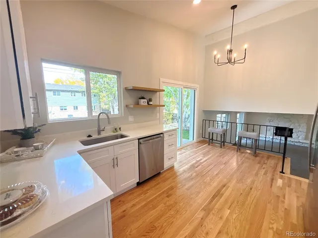 a kitchen with stainless steel appliances granite countertop a stove a sink dishwasher a refrigerator and a dining table with wooden floor