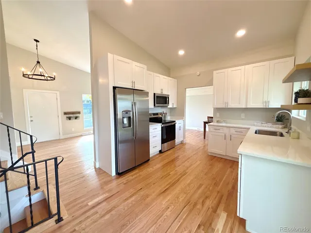 a kitchen with a sink stainless steel appliances wooden floor and a window
