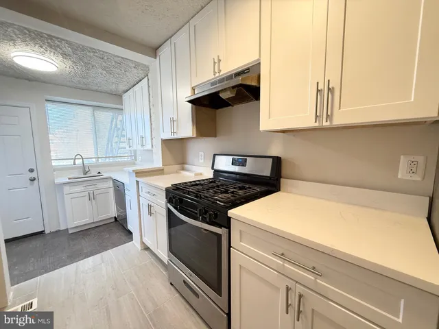 a kitchen with granite countertop white cabinets stainless steel appliances and sink