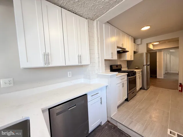 a kitchen with white cabinets and stainless steel appliances