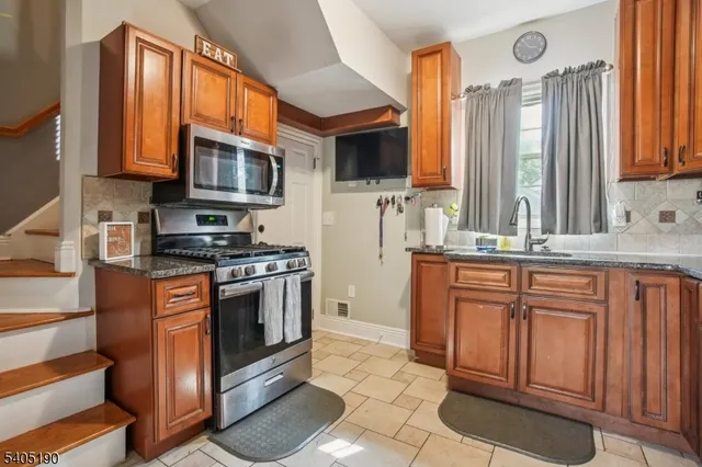 a kitchen with stainless steel appliances granite countertop a stove a sink and a microwave