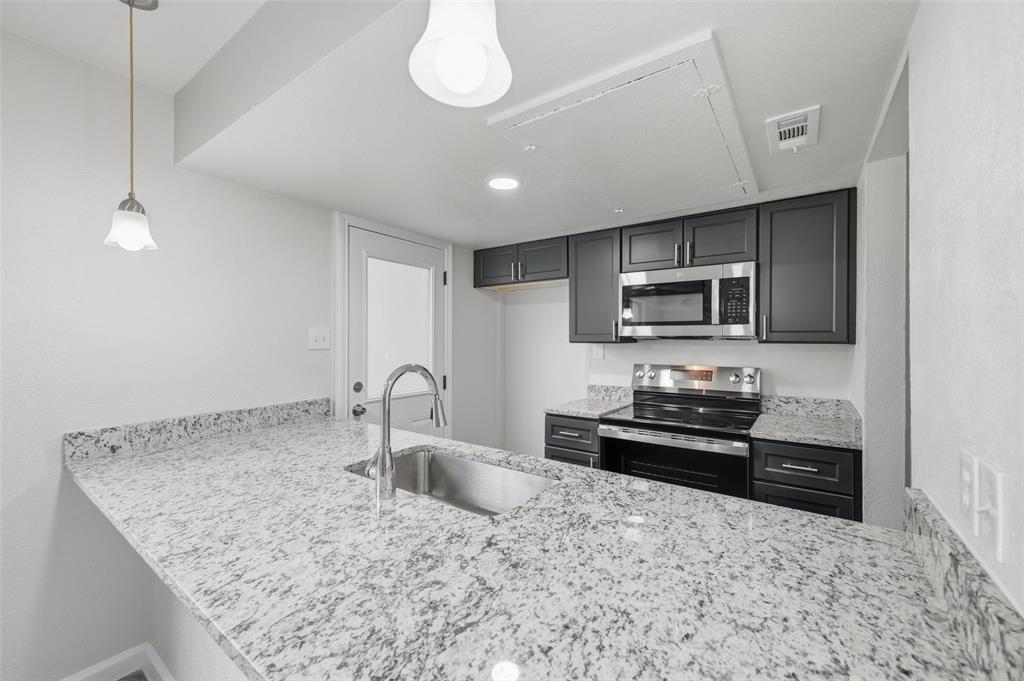 2702 Douglas Avenue, Unit 121 Dallas, TX 75219 - Photo 14 of 34 a kitchen with granite countertop a stove a sink and a microwave