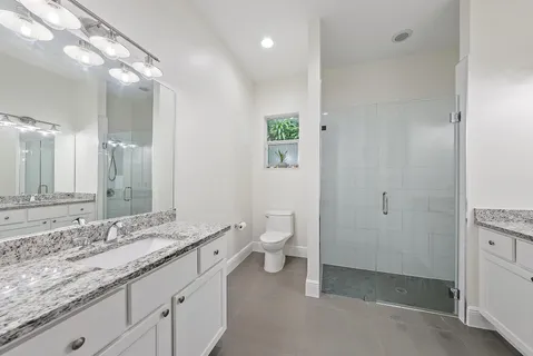 a bathroom with a granite countertop sink a toilet and a mirror