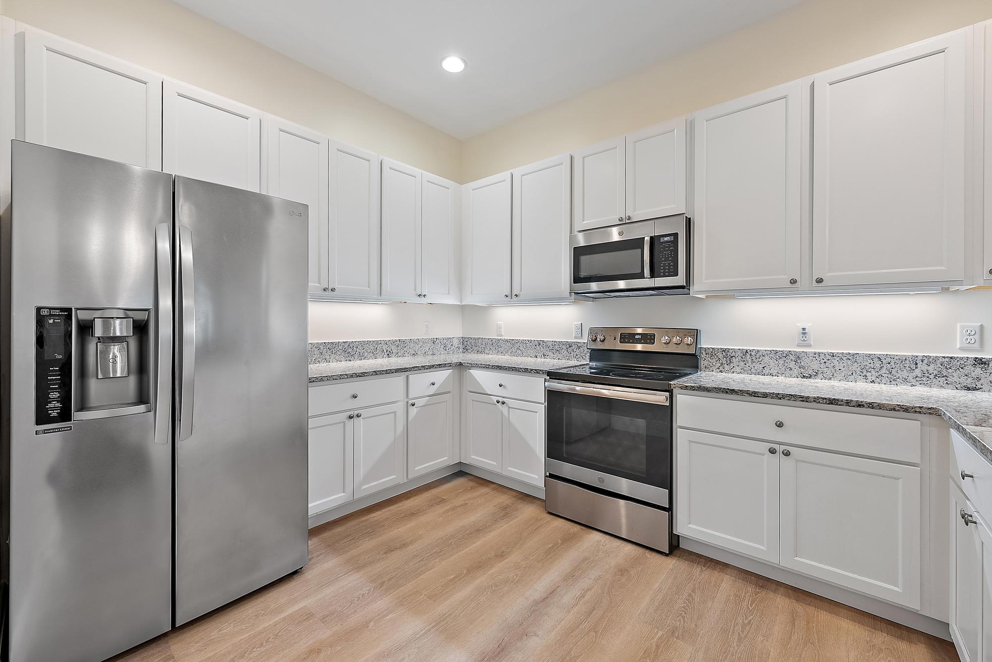 6762 2nd Street Jupiter, FL 33458 - Photo 10 of 27 a kitchen with granite countertop a refrigerator stove and white cabinets