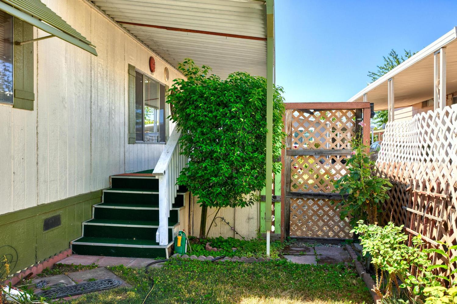 1200 South Carpenter Road, Unit 4 Modesto, CA 95351 - Photo 26 of 31 Exterior entry featuring green carpeted steps, white railing, and a window with green shutters