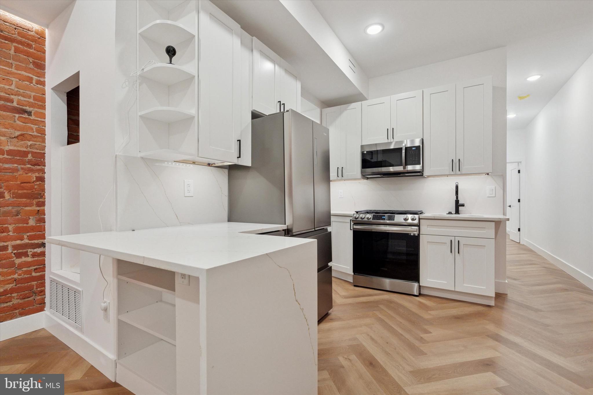 1438 Tasker Street, Unit 1 Philadelphia, PA 19145 - Photo 2 of 16 a kitchen with stainless steel appliances a stove refrigerator sink and microwave