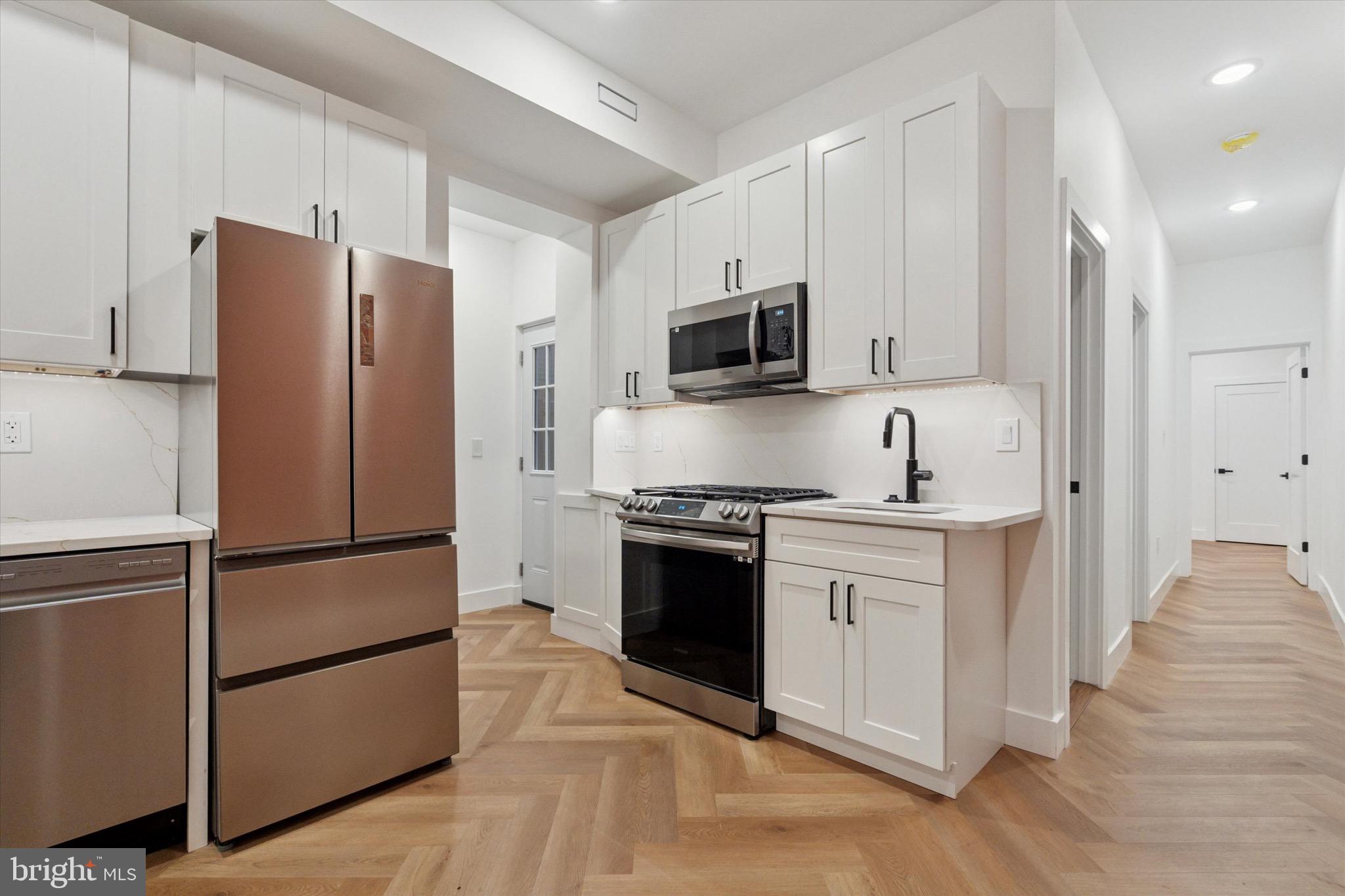 1438 Tasker Street, Unit 1 Philadelphia, PA 19145 - Photo 3 of 16 a kitchen with stainless steel appliances granite countertop a refrigerator stove a sink and a microwave