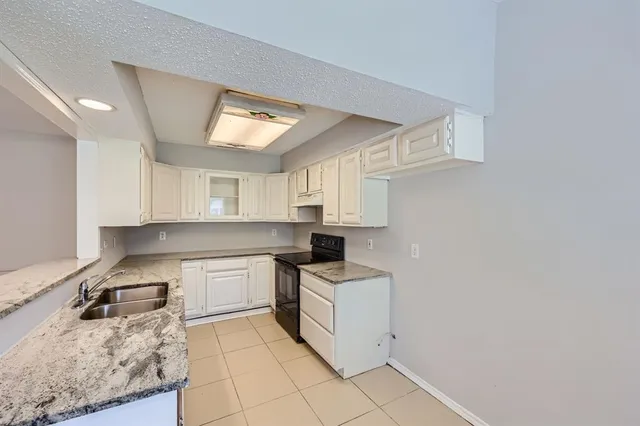 a kitchen with a sink dishwasher stove and white cabinets