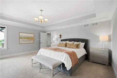 a bedroom with a bed a chandelier and a couch