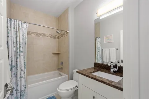 a bathroom with a granite countertop sink toilet mirror and shower