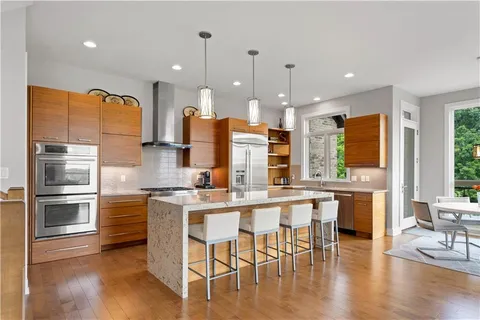 a kitchen with stainless steel appliances granite countertop a stove top oven a sink dishwasher and a refrigerator with wooden floor