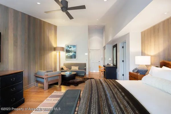 a bed sitting in a spacious bedroom next to a window with pc on the floor