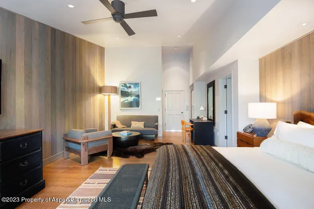 a bed sitting in a spacious bedroom next to a window with pc on the floor