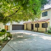 a front view of a house with a garden and trees