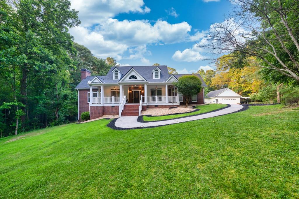 a front view of a house with garden and trees