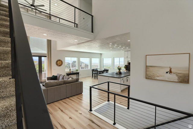 828 South Deer Road Tooele, UT 84074 - Photo 28 of 51 Open-concept living space featuring high ceilings, wood-finish flooring, and abundant natural light from multiple windows and glass doors