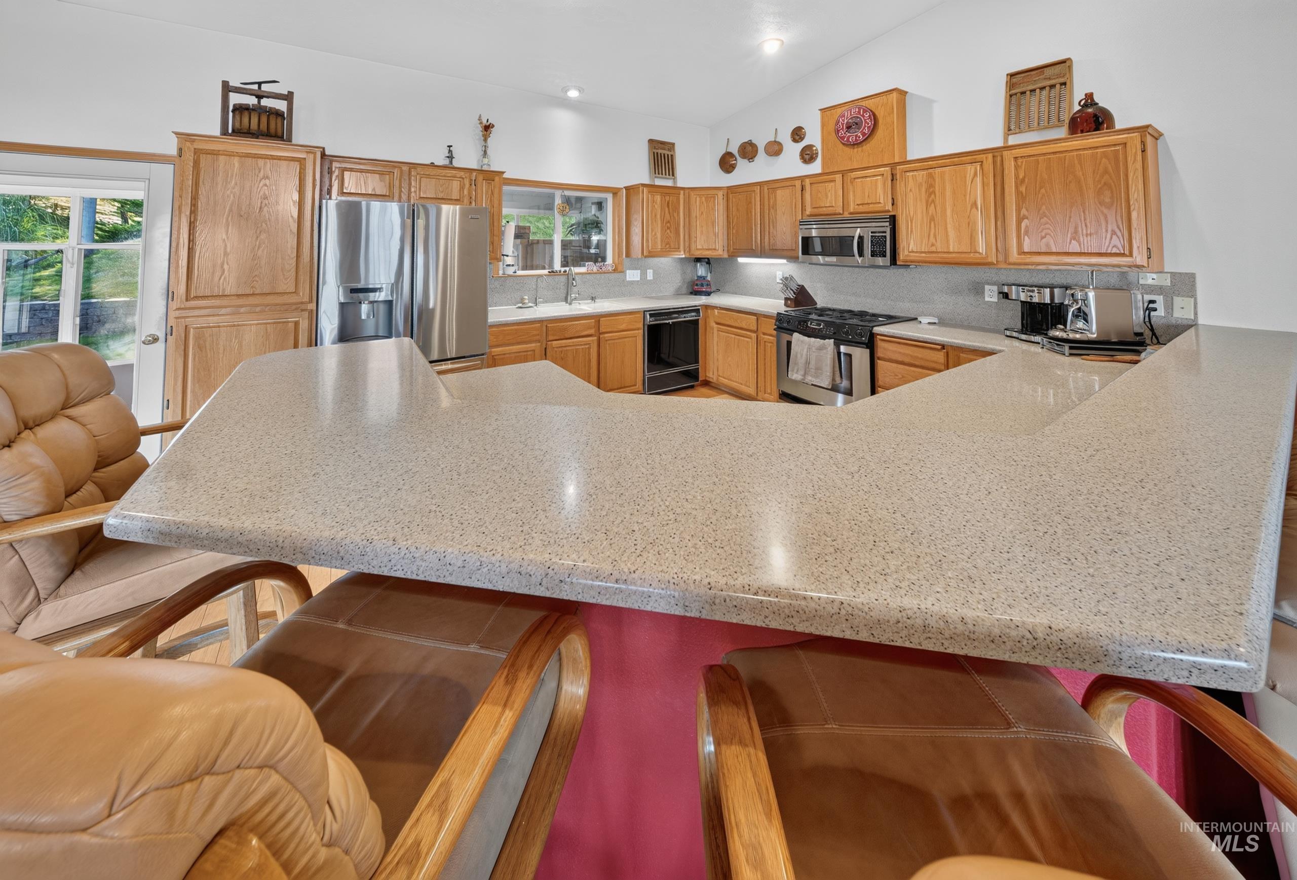 5540 Finley Road Fruitland, ID 83619 - Photo 31 of 50 Kitchen featuring an extended peninsula with light-toned countertops, wood cabinetry, stainless steel appliances, and a tiled backsplash