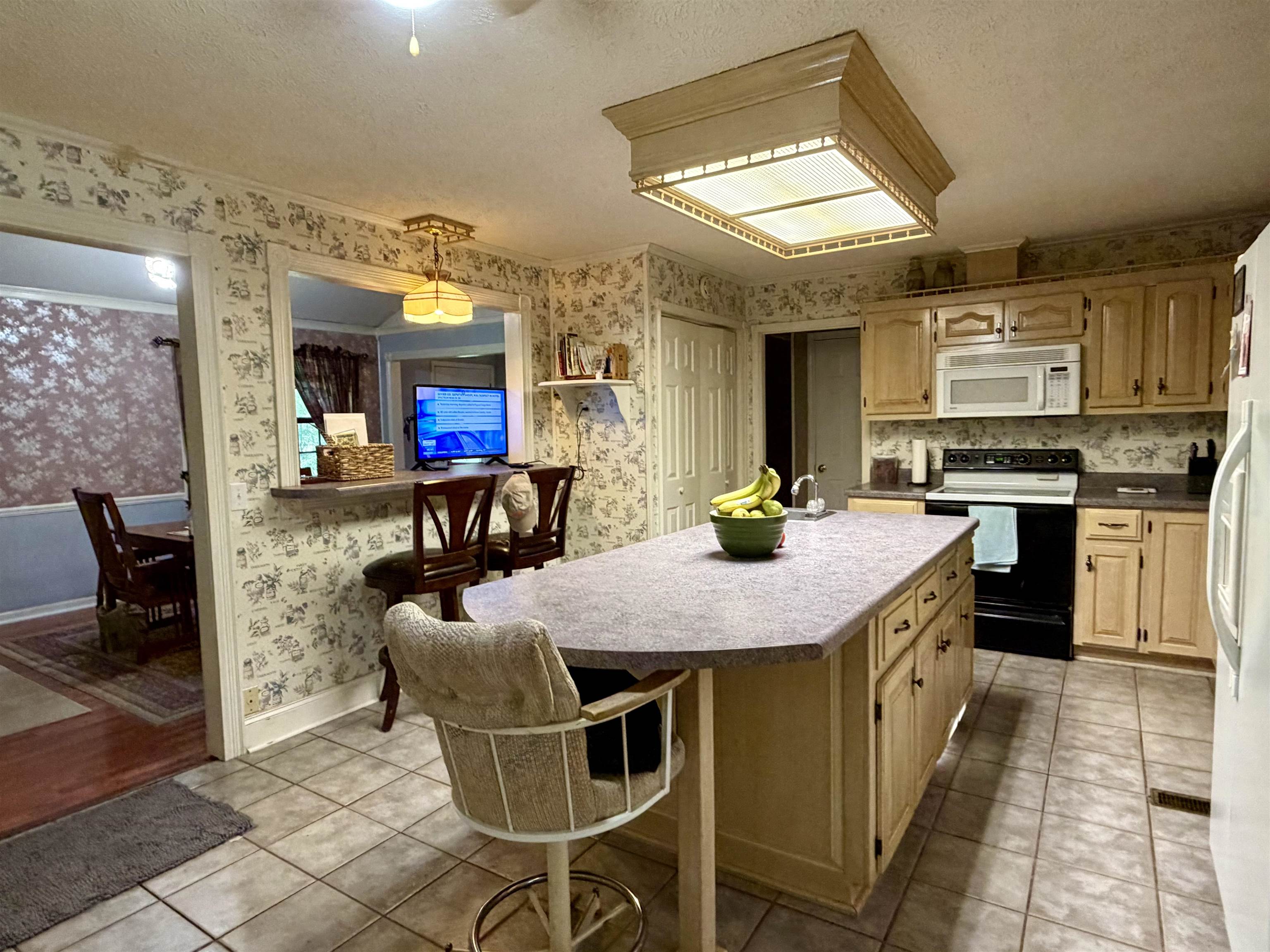 373 Clarence Barham Road Bethel Springs, TN 38315 - Photo 7 of 28 Kitchen featuring a center island with bar seating, overhead fluorescent lighting, wood-finish cabinetry, built-in microwave, and tile flooring