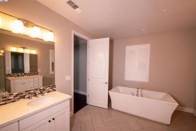 a spacious bathroom with a tub sink and mirror